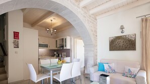 A modern kitchen with white cabinets, a dining table with chairs, and a staircase leading to an upper level. - Villa Katerina Dio in Asteri (Rethymno)
