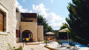 A stone building with a pool area, outdoor seating, and umbrellas. - Villa Marcos Chara in Asteri (Rethymno)