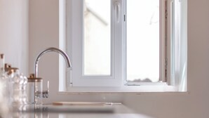 Et moderne køkken med en spejlen­de bordplade, et vindue med udsigt og en hane i rustfrit stål.
