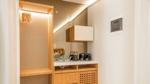 A compact kitchen with wooden cabinetry, a countertop, and a coffee maker.