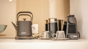 A kitchen area with a coffee maker, a kettle, and a thermos.