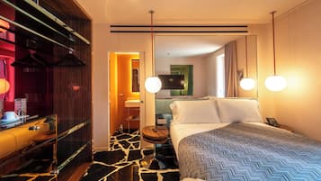 A hotel room with a bed, bedside table, and a mirror.