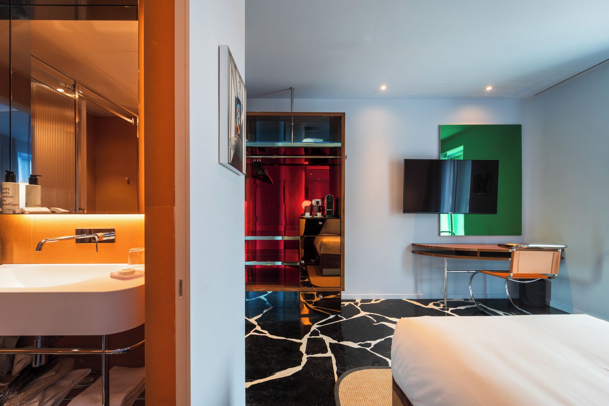 Habitación de hotel moderna con un baño amplio, una cama, un escritorio y un televisor.