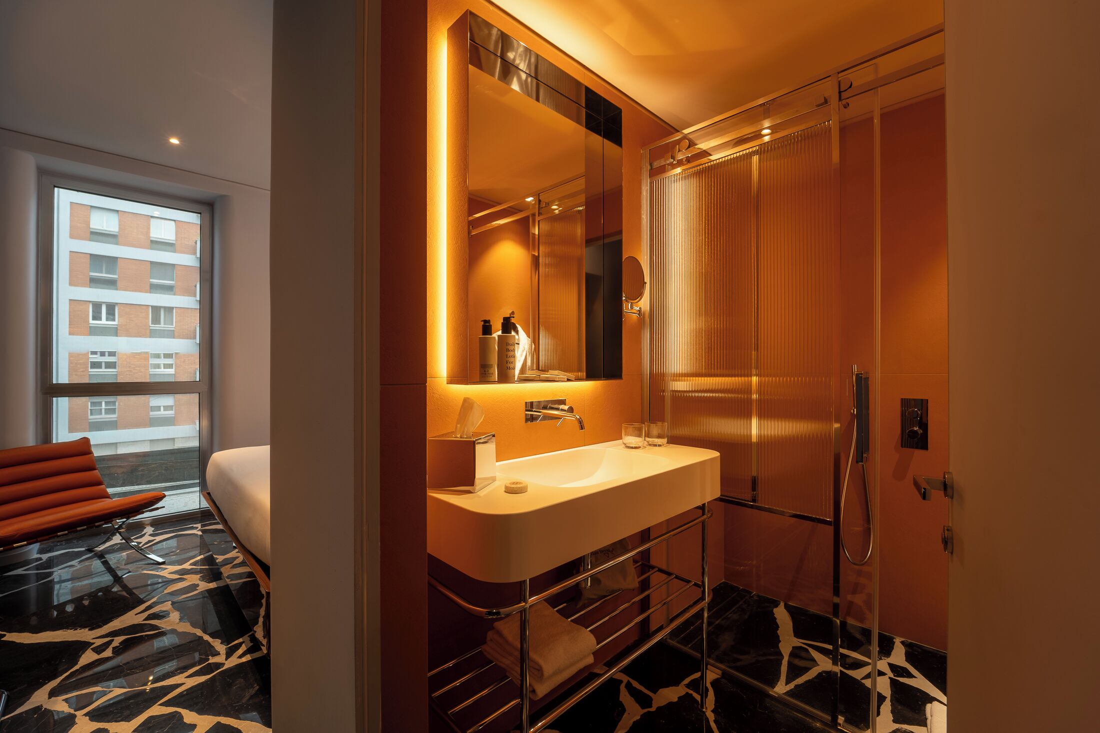 A modern bathroom with a large mirror, white sink, and a shower.
