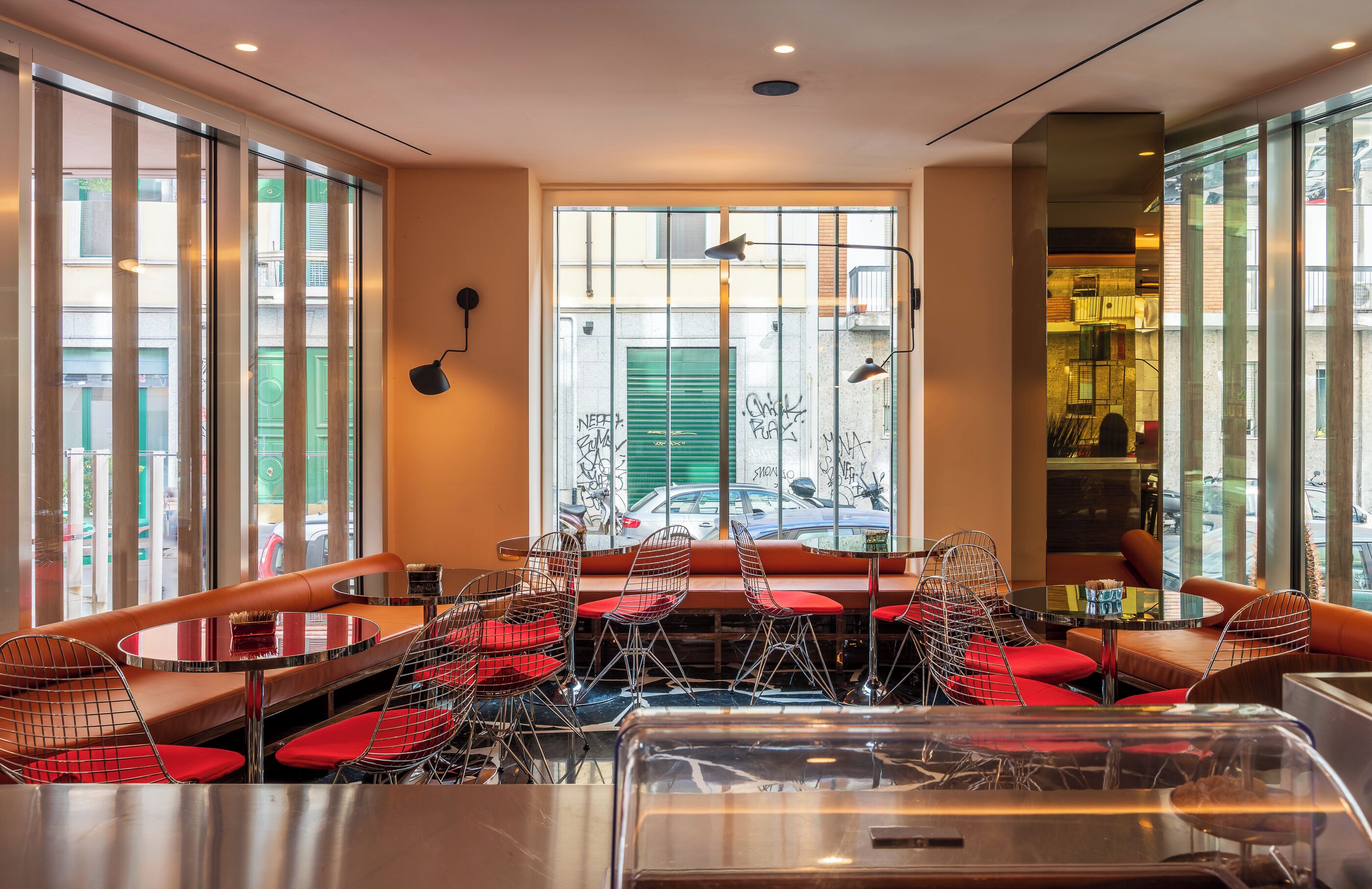 Un restaurant moderne doté d’un espace de restauration central, de grandes fenêtres et d’une vue sur la rue.