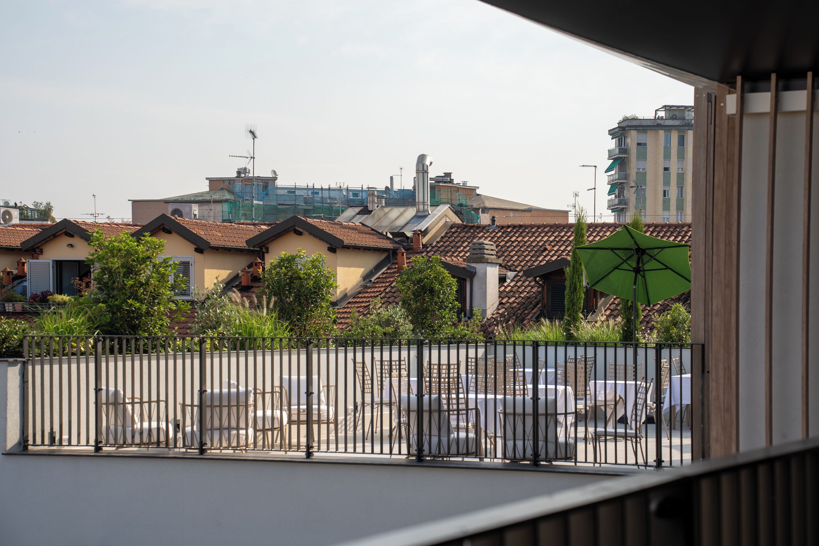 A balcony with a view of a cityscape, including buildings with tiled roofs and a green umbrella.