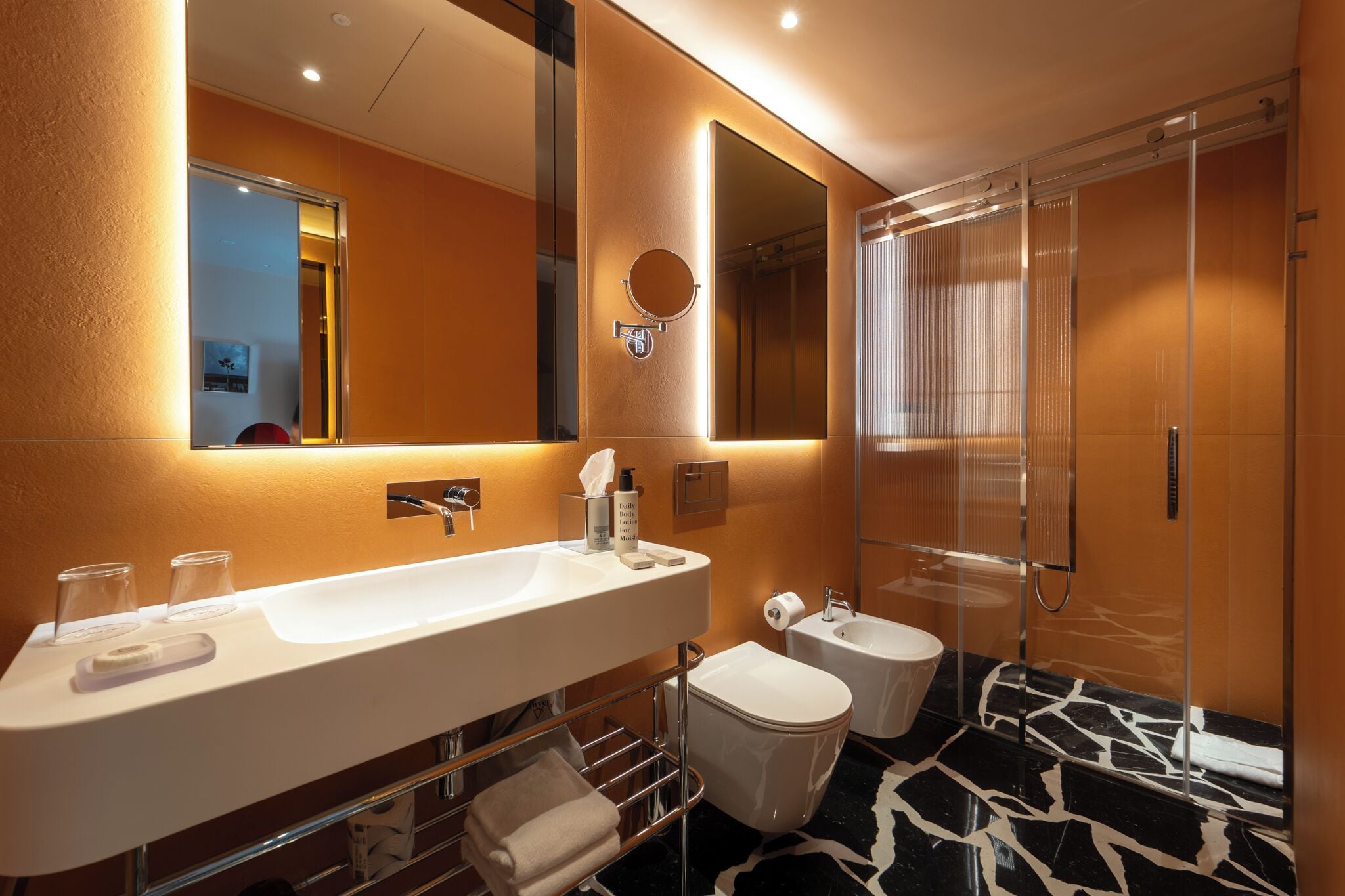 Un baño moderno con un lavamanos grande, un espejo, un inodoro y una ducha.