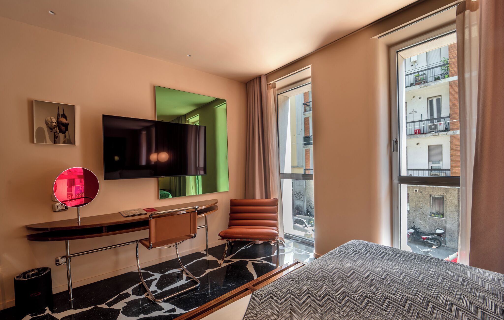 Une chambre d’hôtel moderne dotée d’une grande fenêtre, d’un téléviseur à écran plat, d’un bureau avec une chaise et d’un lit.