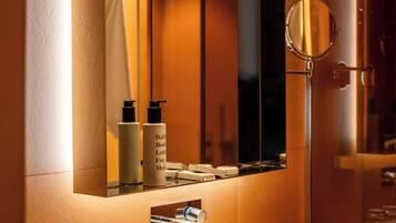 A modern bathroom with a large mirror, a white sink, and a tissue box.