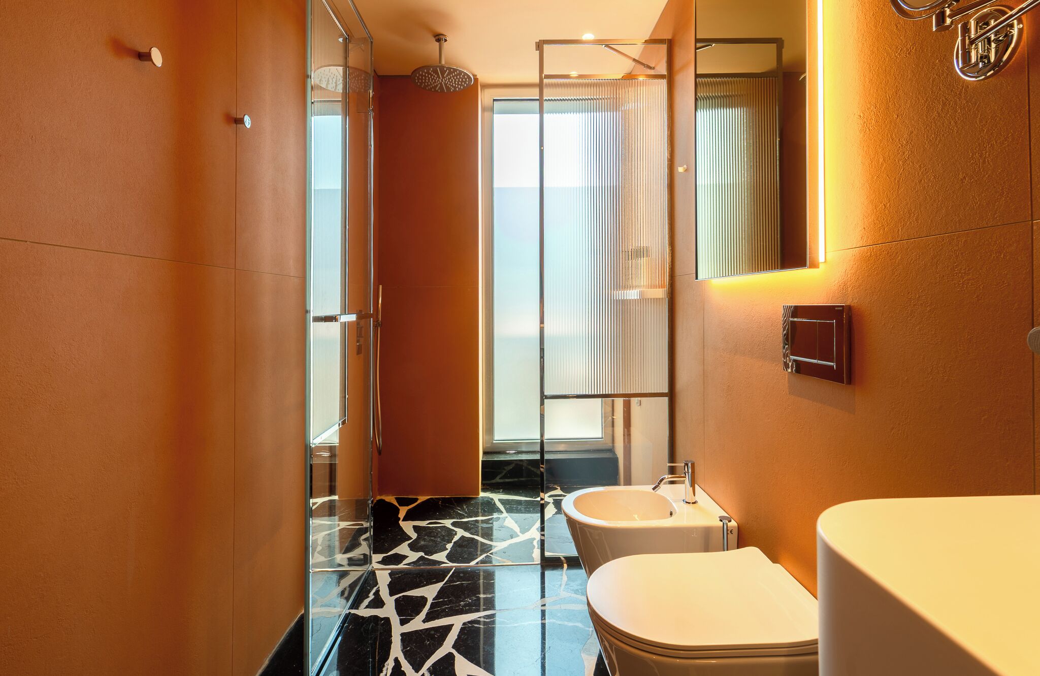 Un baño moderno con cabina de ducha de vidrio, un lavabo blanco y un inodoro.