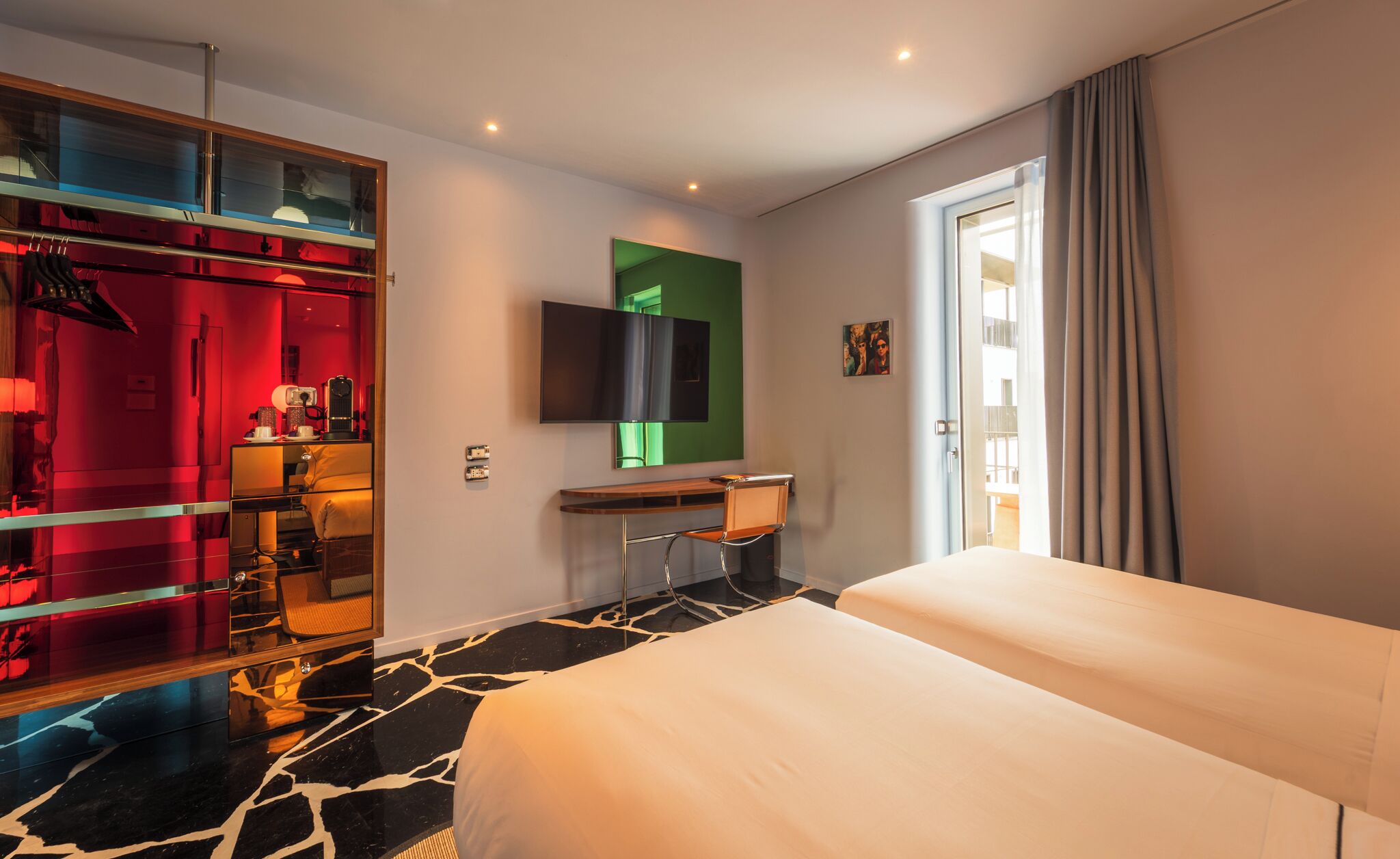 A hotel room with a bed, a desk, a TV, and a wardrobe.