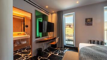 Una camera d'albergo con bagno, una scrivania, un letto e vista sulla città.