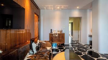 Un salón moderno con pared de madera, sofá de cuero, mesa de centro de cristal y suelo de mármol.
