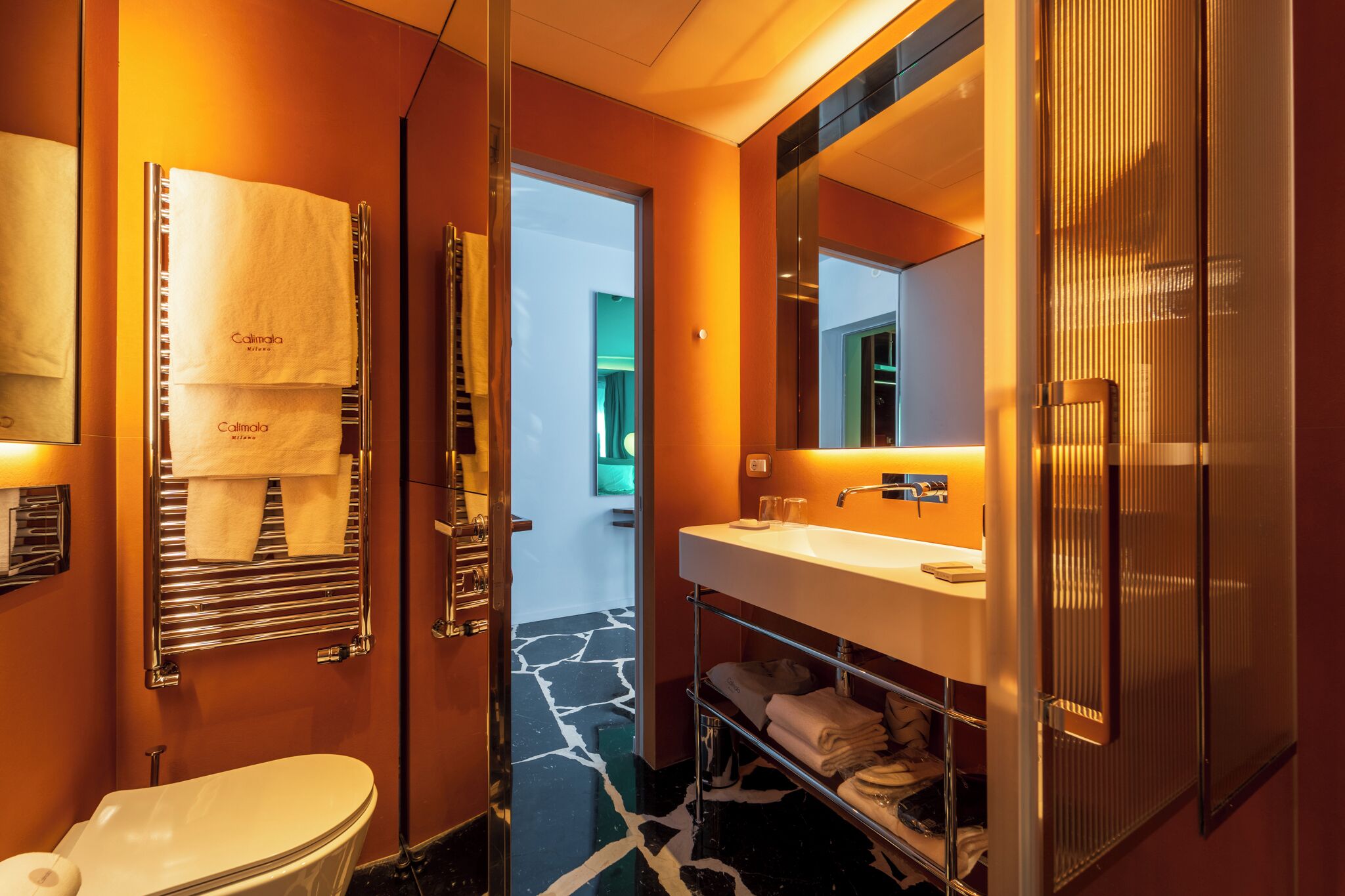 Une salle de bain moderne avec un lavabo blanc, un grand miroir et un porte-serviettes.