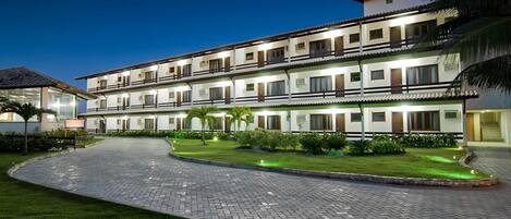 A multi-story hotel with a paved courtyard and well-maintained lawn.