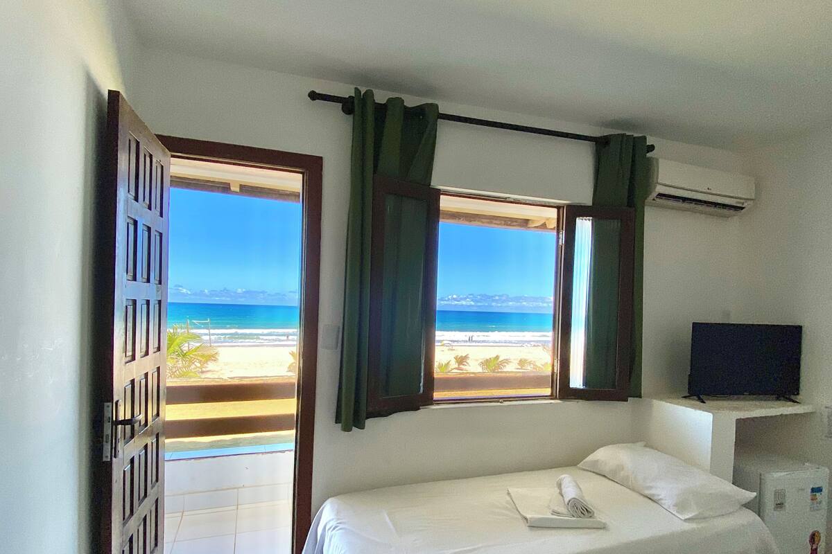 Une chambre avec un lit, une télévision et vue sur la plage.