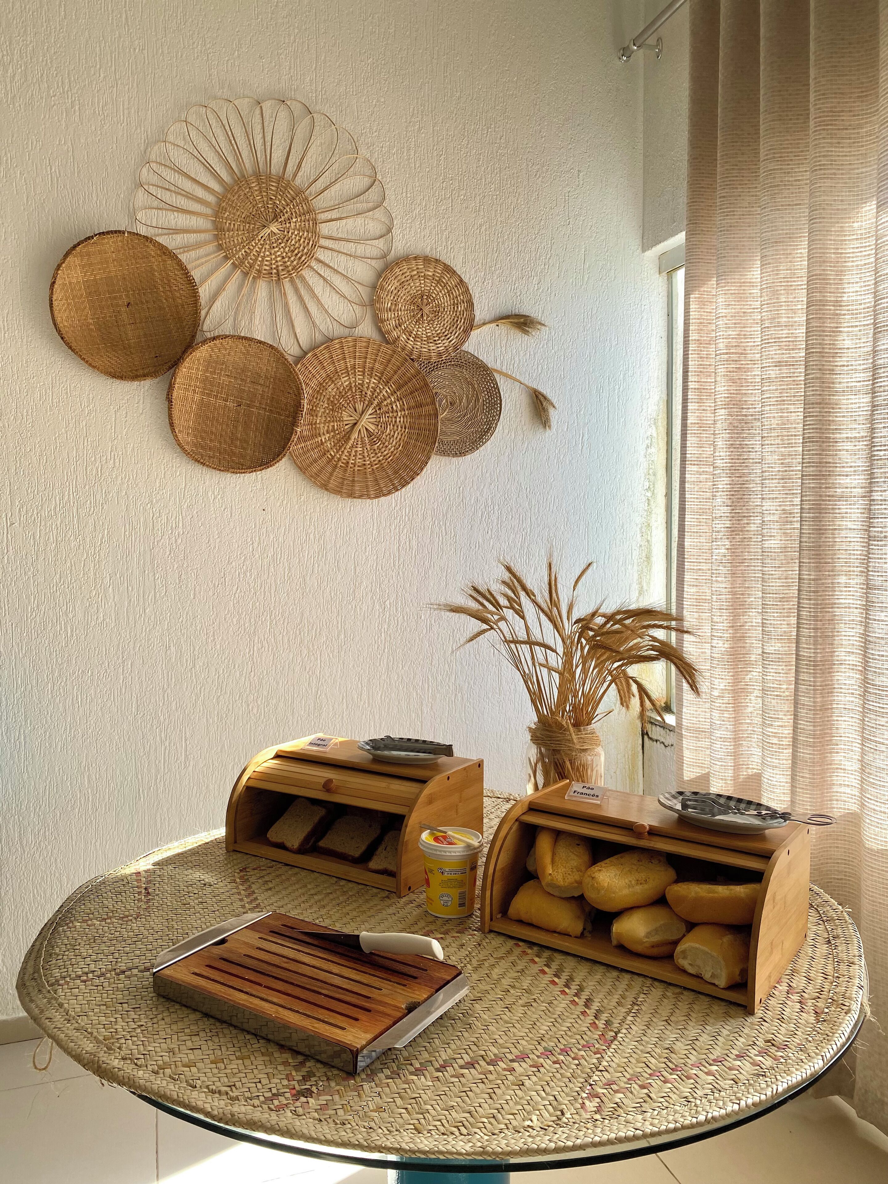 A round table with woven placemats, bread baskets, and a jar of jam.