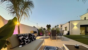 Un espacio al aire libre con una sala y sillas, una parrilla y un tapete estampado.