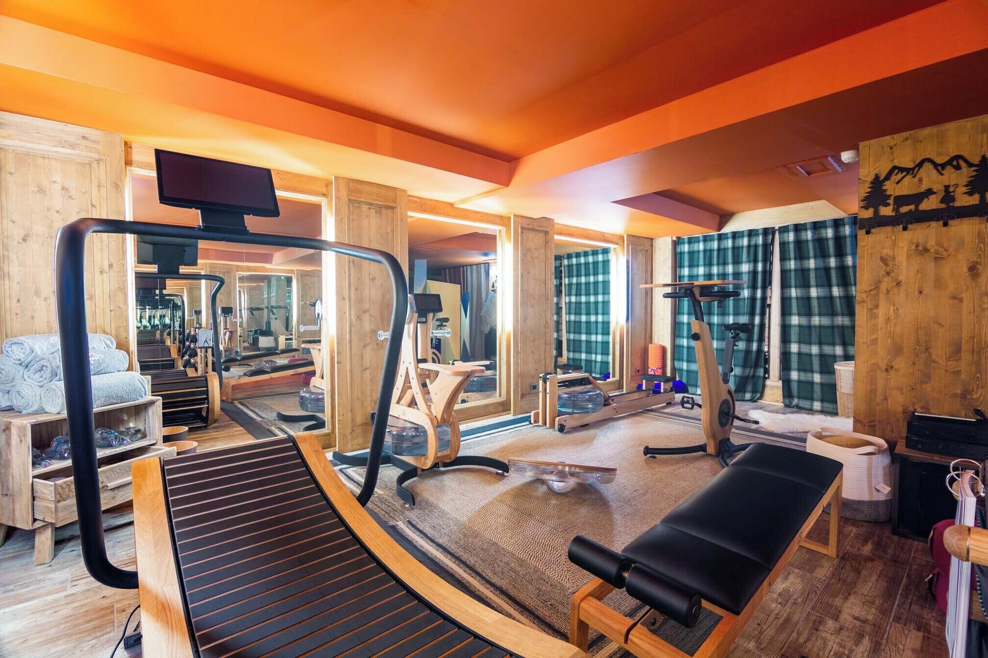 Un gimnasio con equipo de ejercicio, una cinta de correr y una banca.