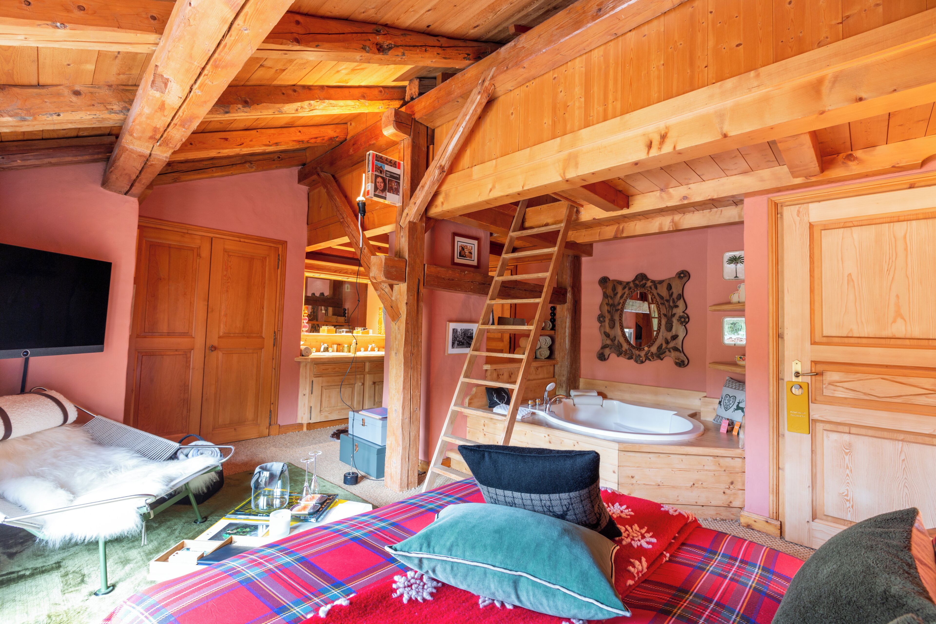 Una habitación acogedora con una cama, una escalera de madera, un lavamanos y un televisor.