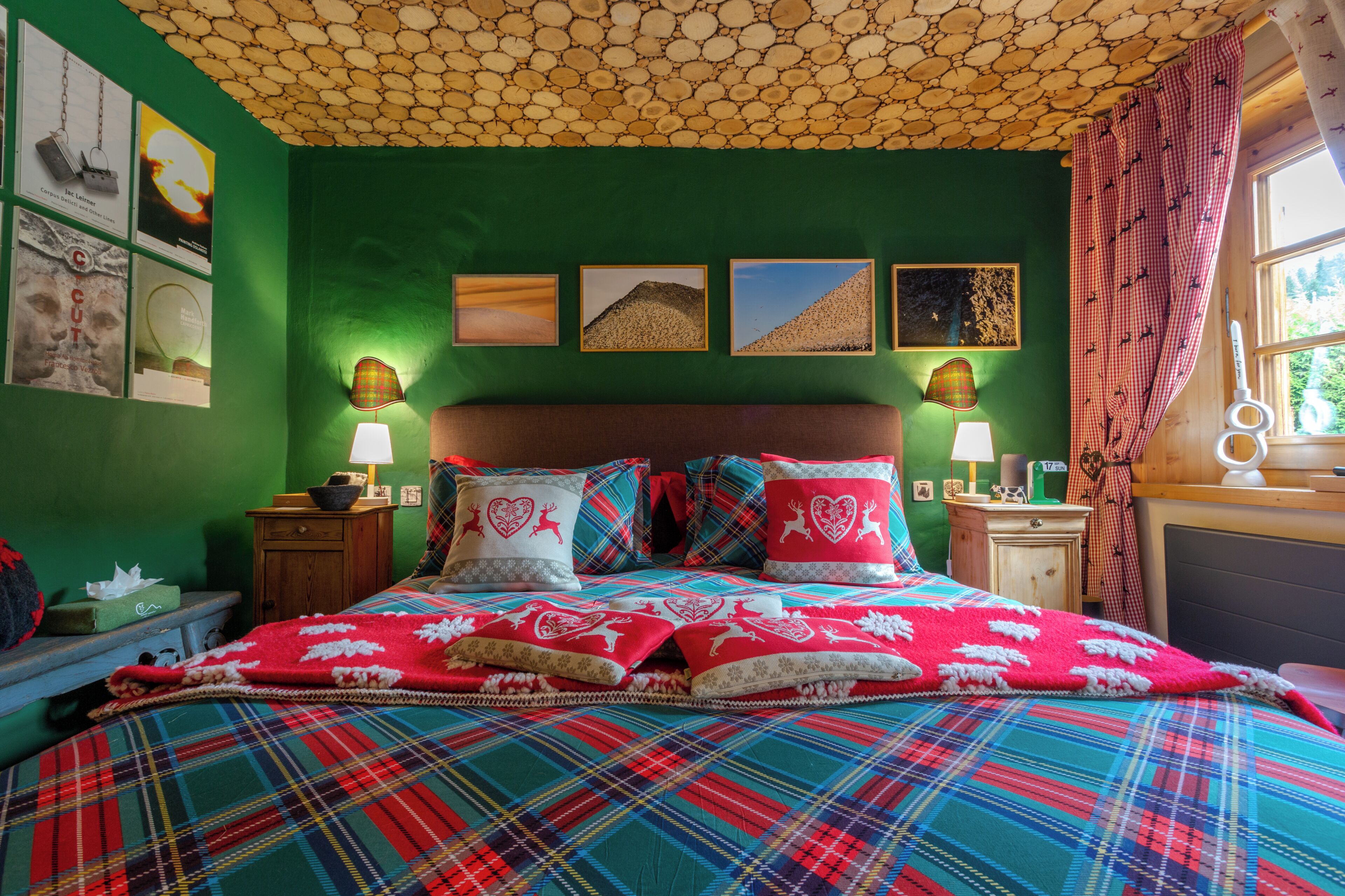 Una habitación con pared verde, cama con cubrecama escocés y techo de piedra.