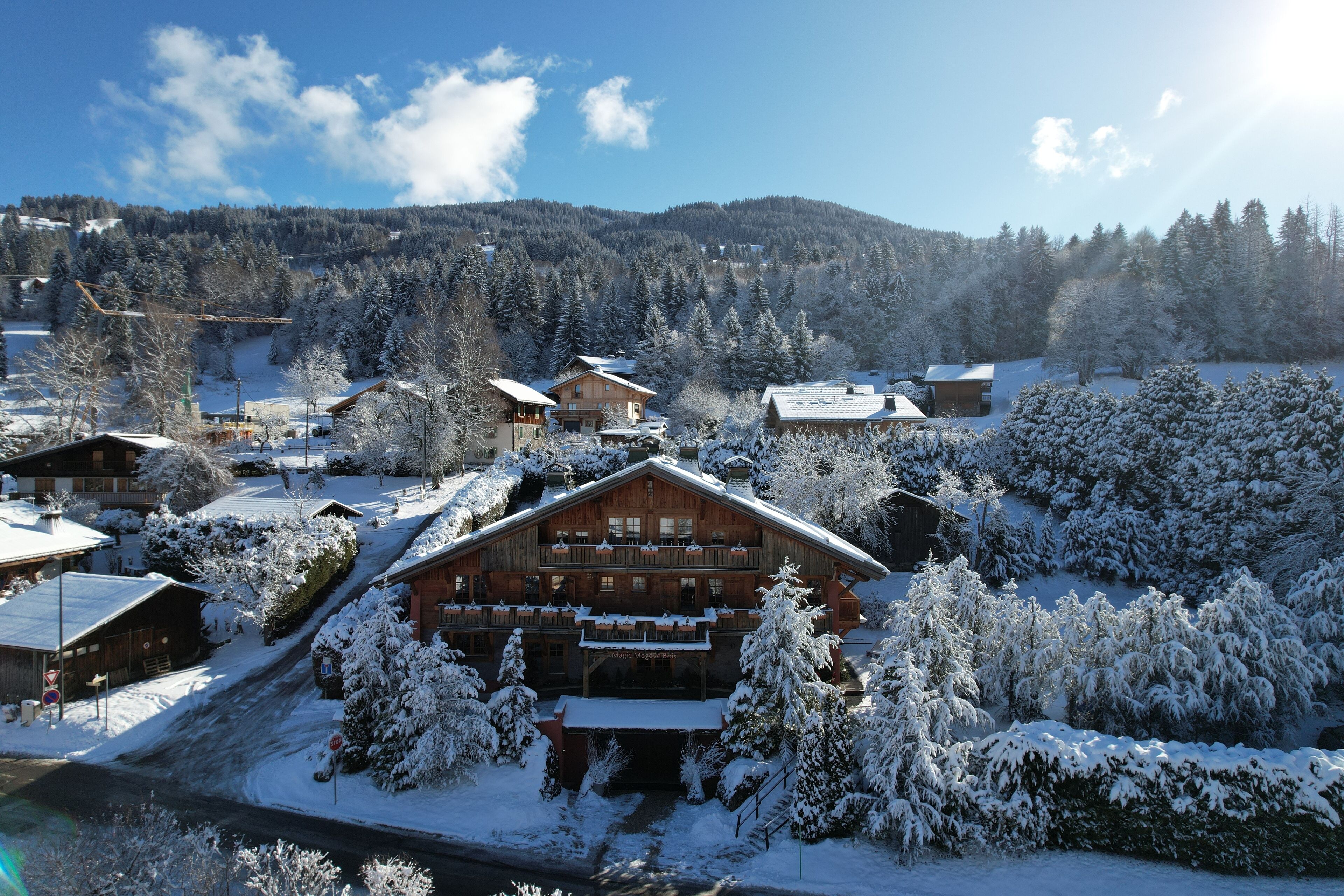 A large wooden lodge with multiple balconies, surrounded by snow-covered trees and a mountainous backdrop.