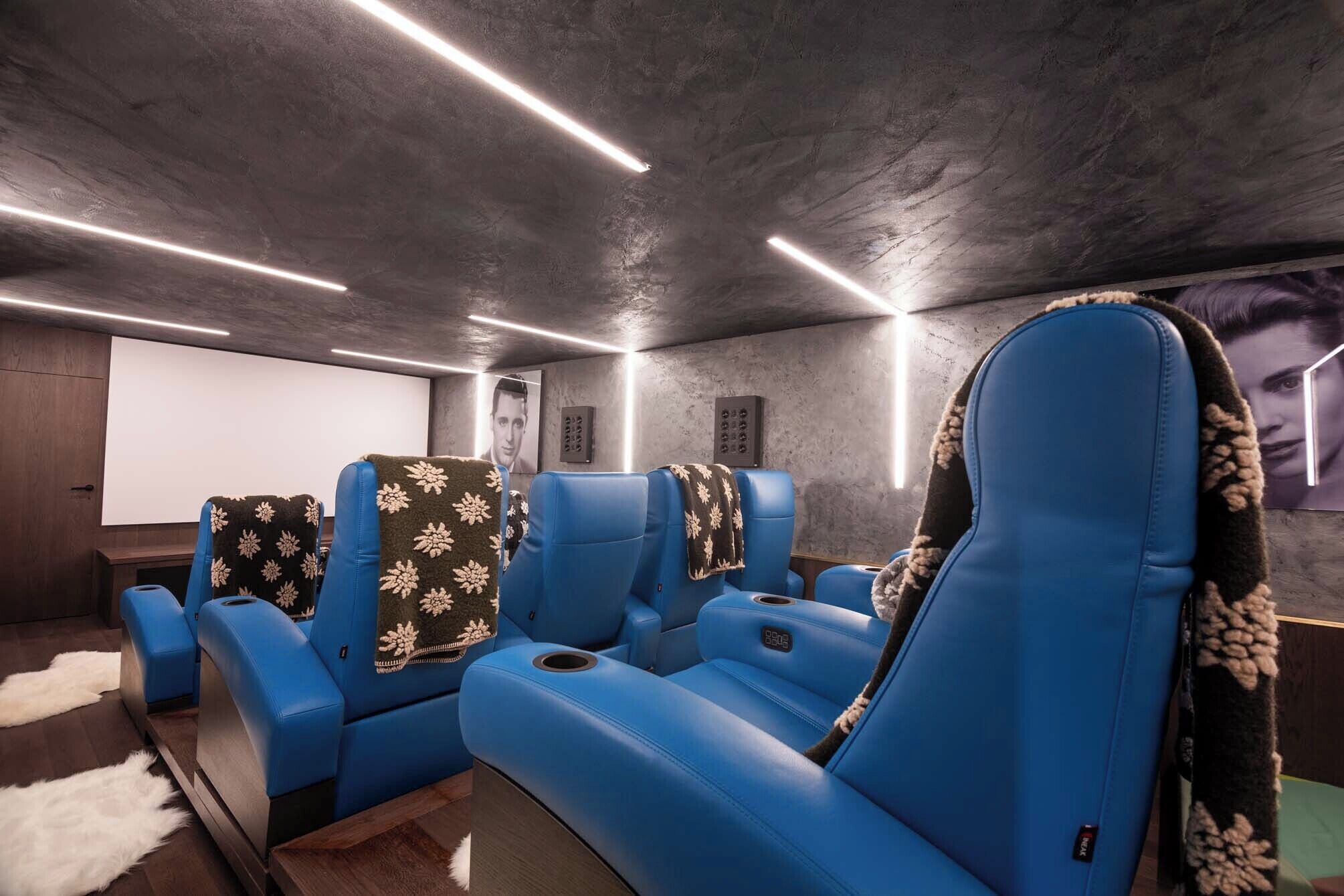 Un cine en casa con asientos de cuero azul, una pantalla grande y un piso alfombrado acogedor.