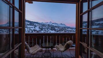 A wooden deck with a table and chairs, overlooking a snowy mountain landscape.