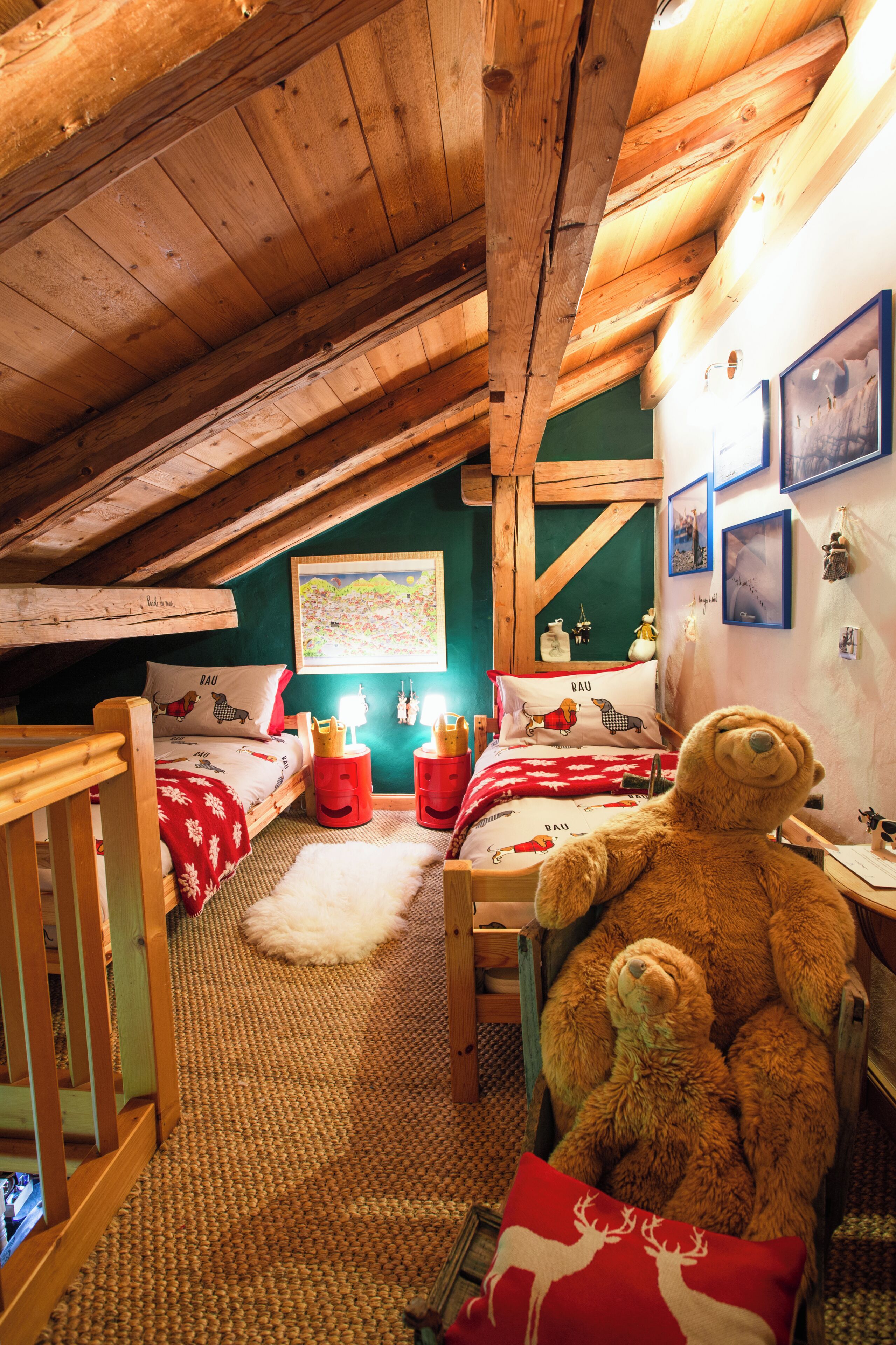 A cozy attic bedroom with wooden beams, a bunk bed, a large teddy bear, and a map on the wall.