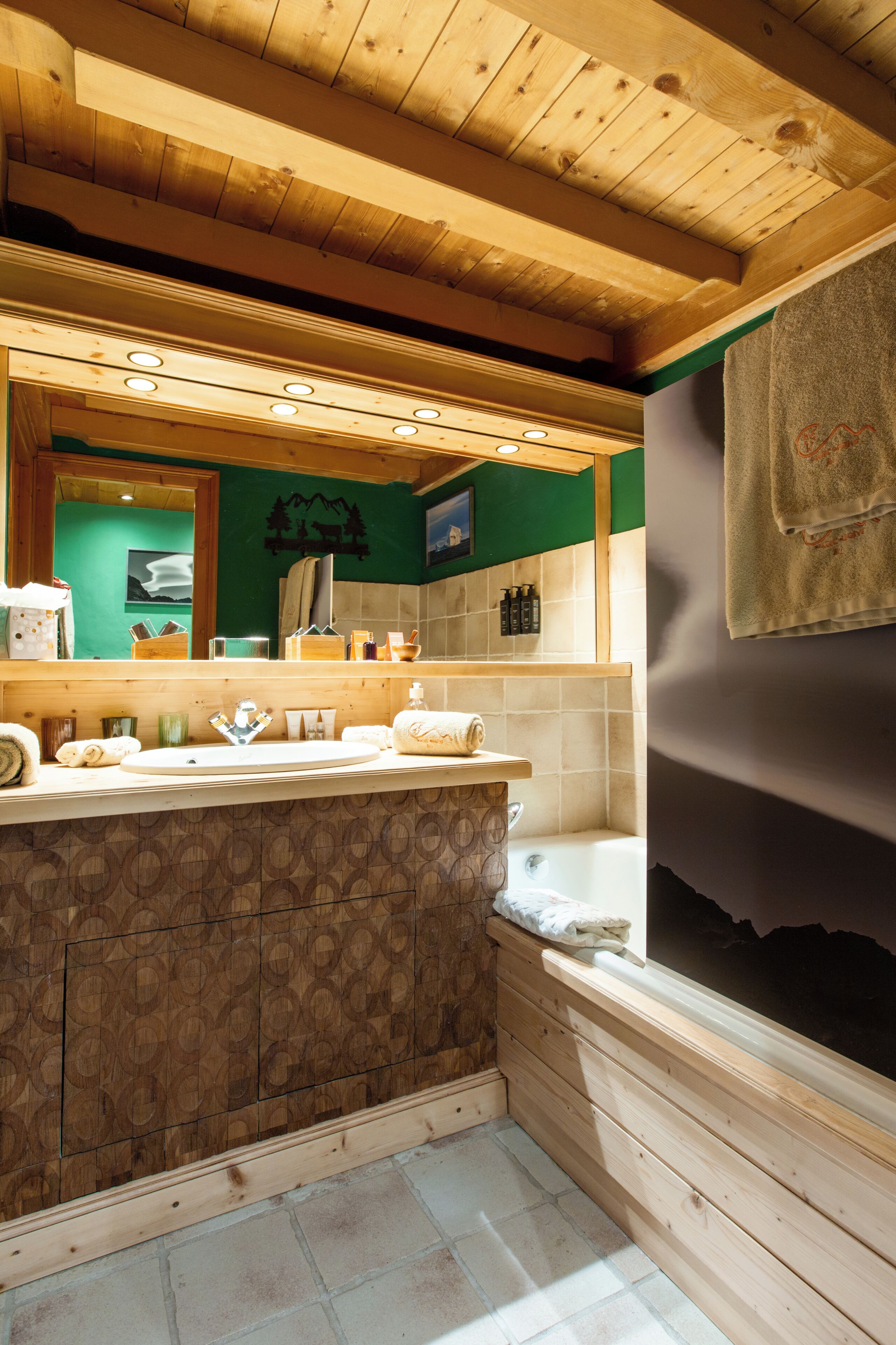 Ein Badezimmer im Holzblockhaus-Stil mit einem Holzbadezimmer-Möbel, einer Badewanne und einem Spiegel über dem Waschbecken.