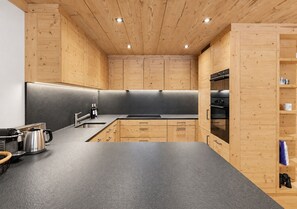 A modern kitchen with wooden cabinetry, a black countertop, and stainless steel appliances.