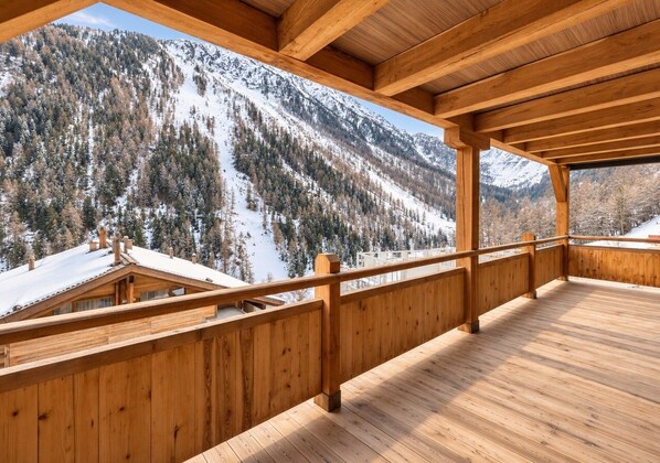 A wooden deck with a view of snow-covered mountains.