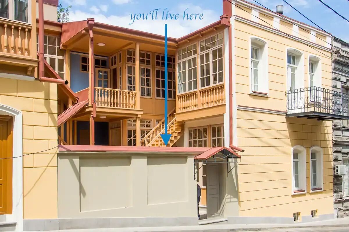 A yellow building with a balcony and a staircase.