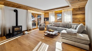 A cozy living room with a wooden floor, a sofa, a coffee table, and a fireplace. - Chalet Larchwood by Mrs Miggins 3 (Grimentz)