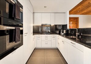 A modern kitchen with white cabinetry, a black countertop, and stainless steel appliances.