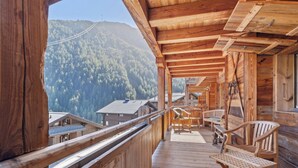 Un balcón de madera con vista a una montaña boscosa.