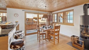Una habitación acogedora con techo de madera, una mesa de comedor con sillas, una chimenea y vistas al exterior.