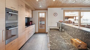 Una cocina moderna con gabinetes de madera, electrodomésticos de acero inoxidable y un amplio ventanal con vistas al exterior.