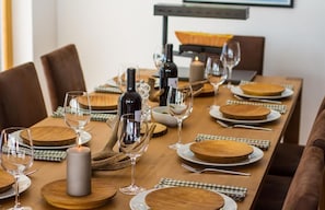 A dining table set with wine glasses, plates, and a candle. - Duplex de Luxe, 5 chambres Rahas A Grimentz - By Mrs Miggins (Grimentz)