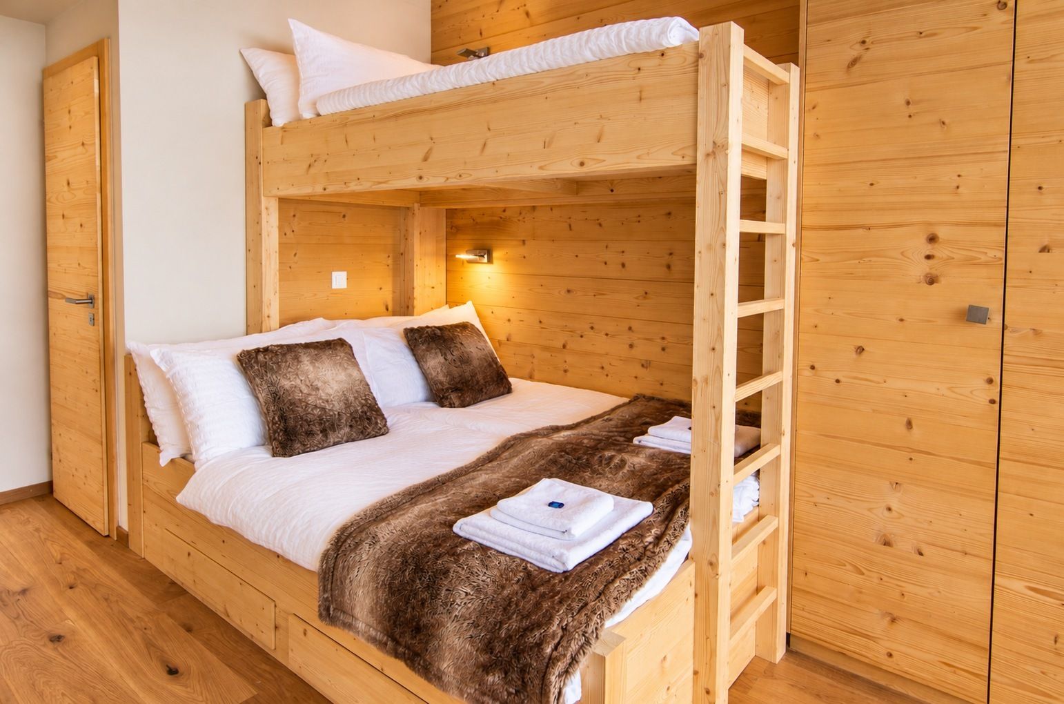Una cama litera con escalera, ropa de cama blanca y una manta de piel.