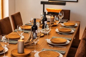 A dining table set with wooden plates, wine glasses, and a candle.