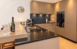 A modern kitchen with a central island, stainless steel appliances, and a wall clock.