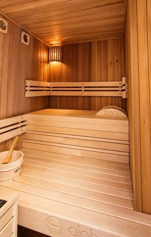 A wooden sauna with a bench, a bucket, and a towel rack.