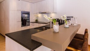 A modern kitchen with a central island, stainless steel appliances, and a vase with flowers.