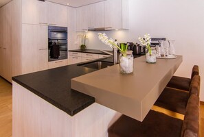 Een moderne keuken met een centraal eiland, roestvrijstalen apparatuur en een vaas met bloemen.