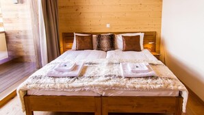 A wooden-paneled room with a bed, two bedside lamps, and a window with curtains.
