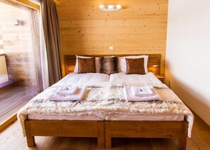 Een kamer met houten lambrisering, een bed, twee bedlampen en een raam met gordijnen.