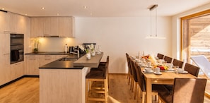 A modern kitchen with wooden cabinets, a central island, and a dining area with a wooden table and chairs.