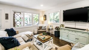 Una sala de estar con sofá, mesa de centro, televisor y aparador.