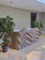 Un mostrador de recepción con un diseño ondulado, una planta en maceta y una puerta al fondo.